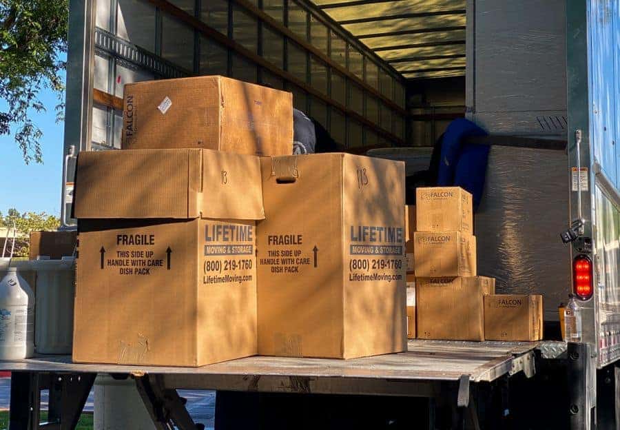 Professional movers loading furniture and boxes into a Lifetime Moving & Storage truck