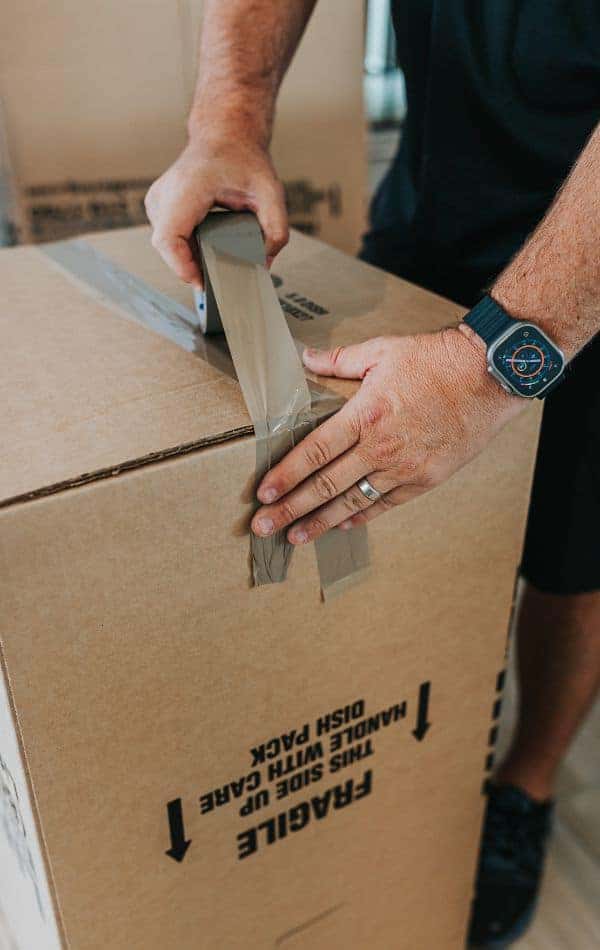 Close-up of a professional mover taping and sealing a moving box before transport